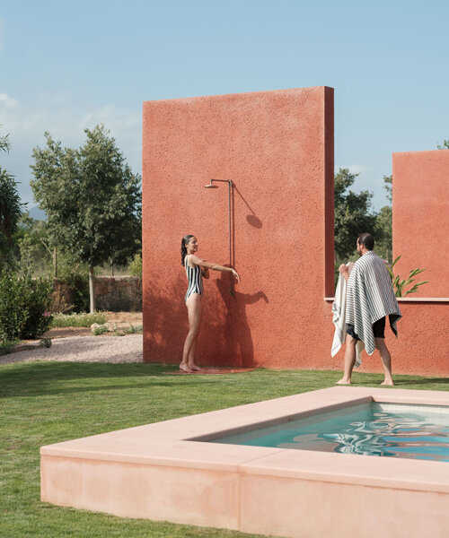 a pink 'lover's house' settles into the rugged landscape of mallorca