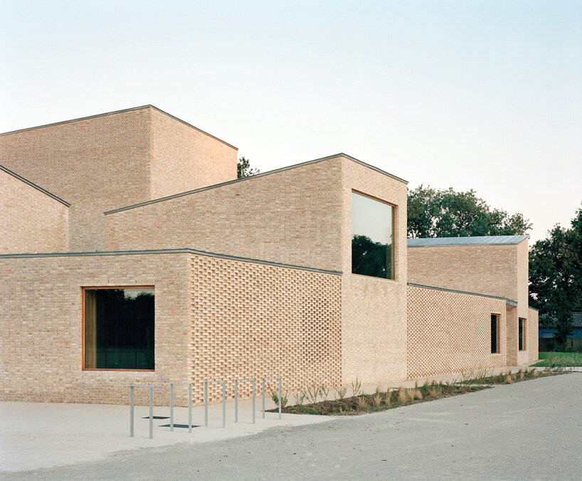 raum architects builds monolithic cultural center in france using terracotta bricks + concrete