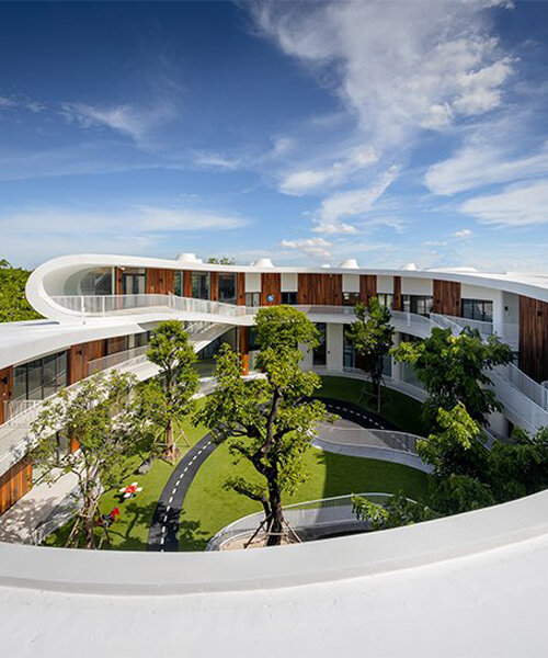 an elliptical-shaped courtyard punctures the kensington learning space in bangkok