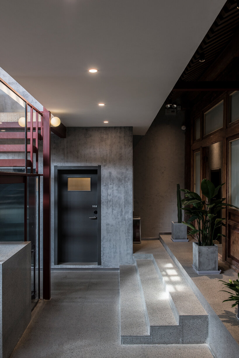 aged wooden roof structure + touches of dark red decorate this hidden hotel in beijing, china