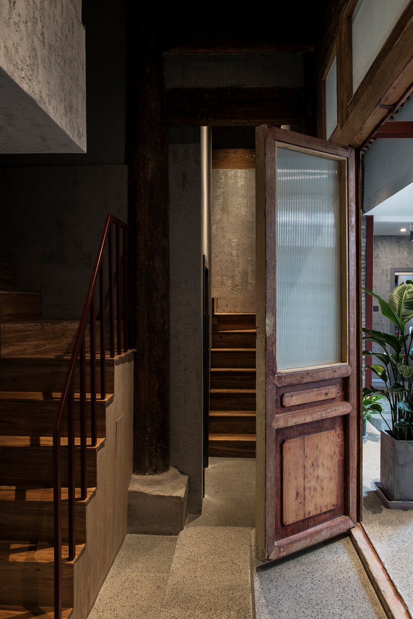 aged wooden roof structure + touches of dark red decorate this hidden hotel in beijing, china