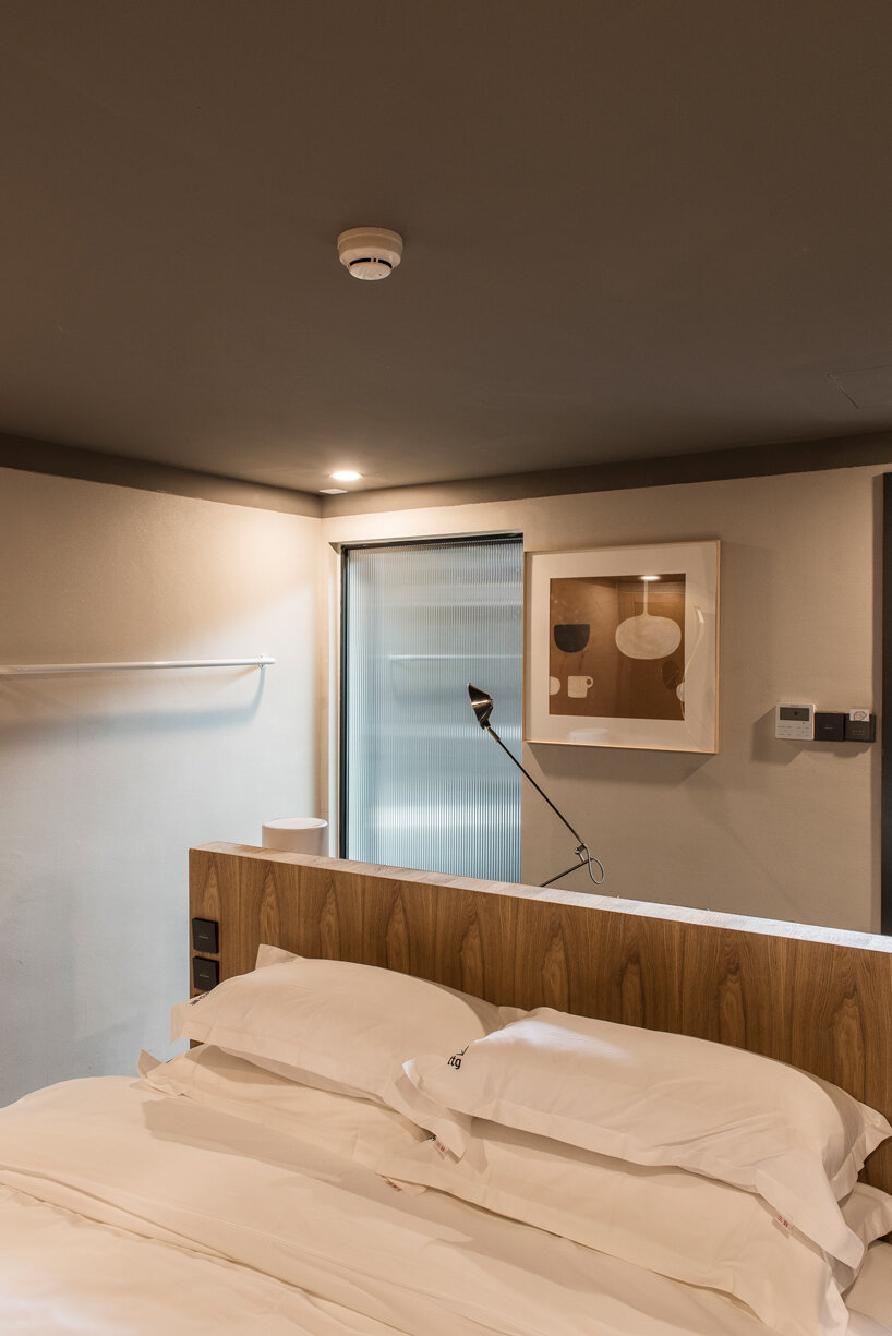 aged wooden roof structure + touches of dark red decorate this hidden hotel in beijing, china