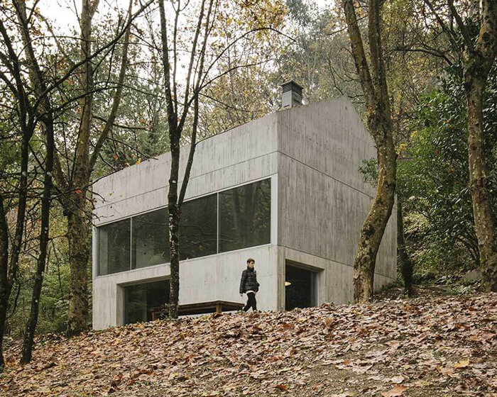carvalho araújo embeds a minimal concrete house into a densely wooded hillside in portugal