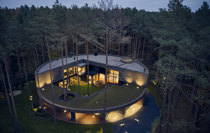 circular wooden house by mobius architekci blends into its pine forest surroundings in poland