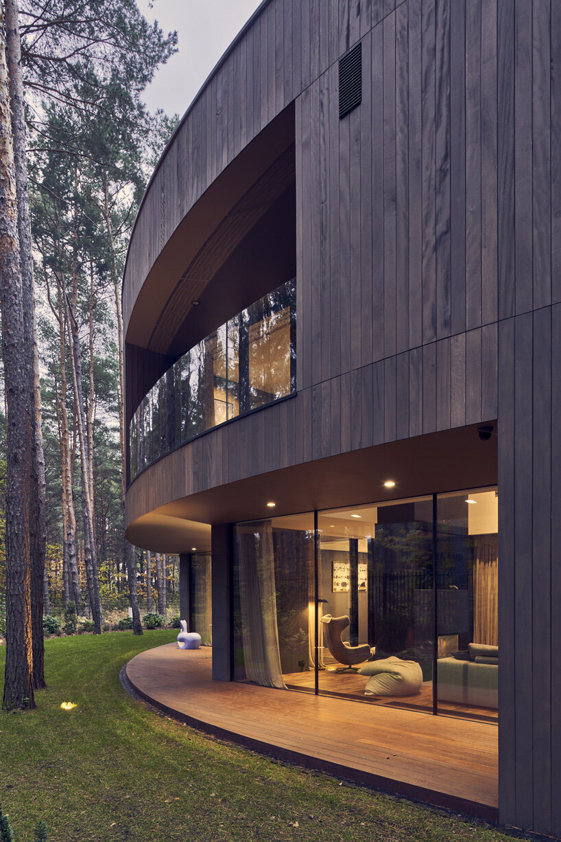circular wooden house by mobius architekci blends into its pine forest surroundings in poland