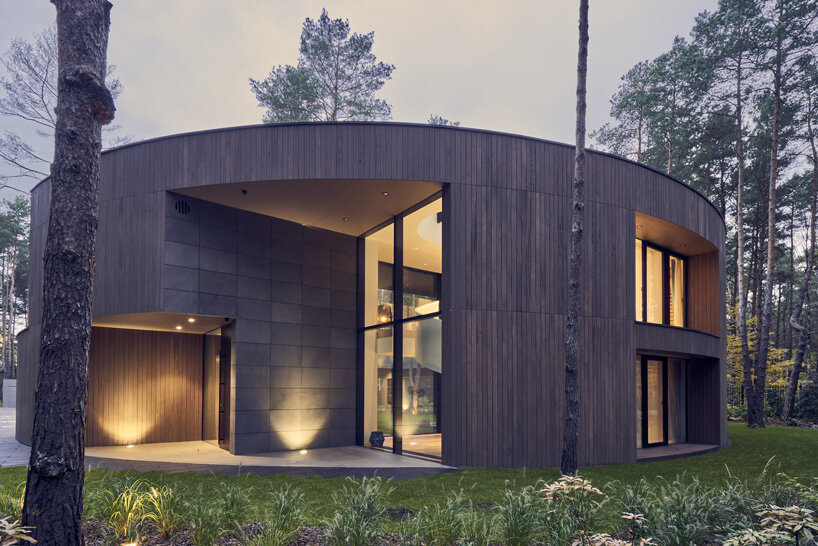 circular wooden house by mobius architekci blends into its pine forest surroundings in poland