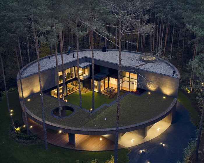 circular wooden house by mobius architekci blends into its pine forest surroundings in poland