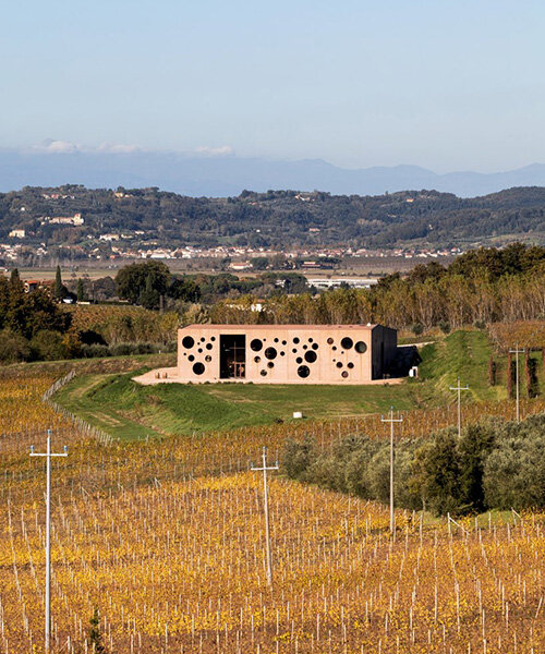 and-studio punctures irregular holes into the concrete façade of this tuscan winery