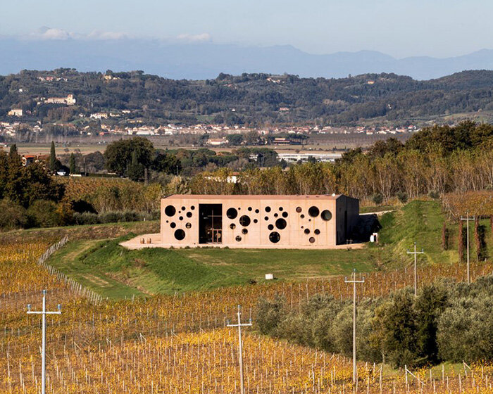 and-studio punctures irregular holes into the concrete façade of this tuscan winery