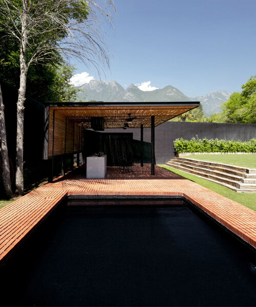 S-AR frames enigmatic black pool with red brick at outdoors pavilion in mexico