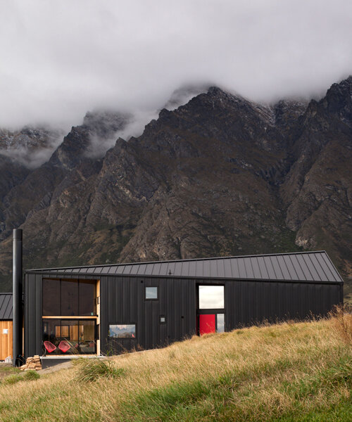 tom's house is an angular black cabin nestled into new zealand's mountain landscape