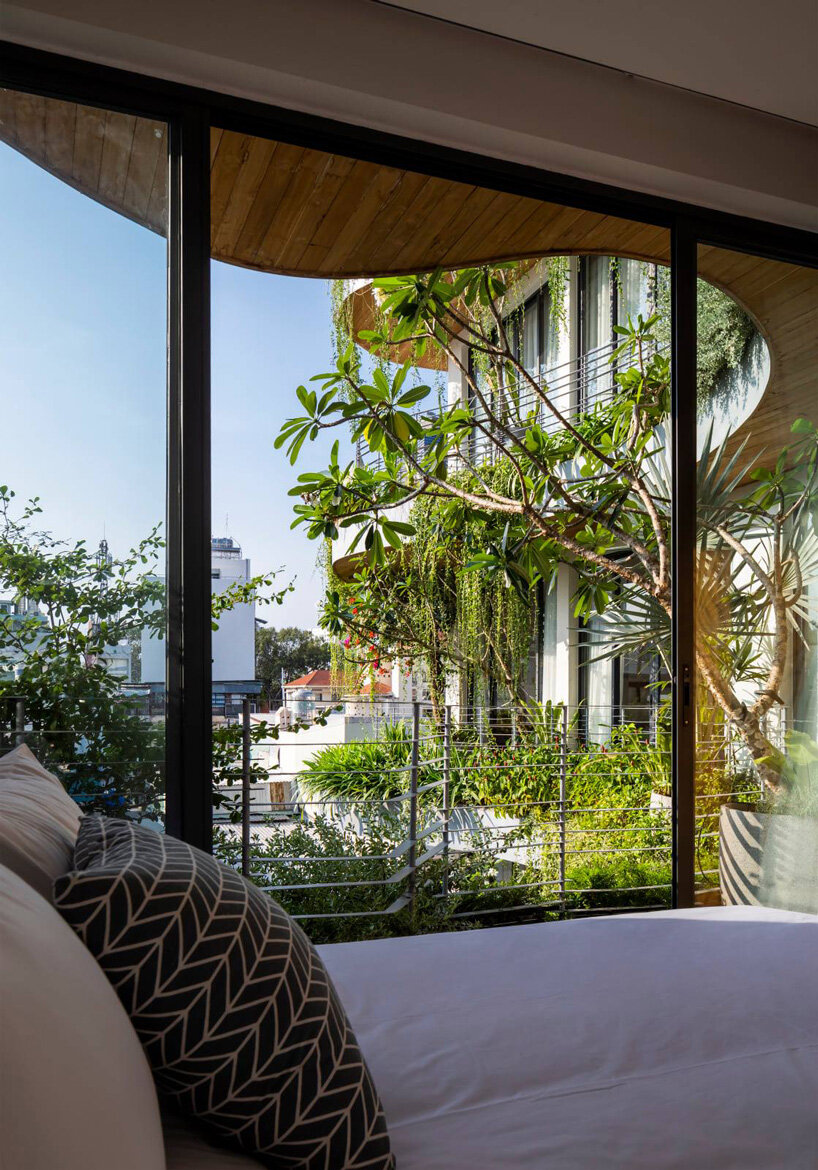 tropical plants cascade from the undulating balconies of this apartment building in vietnam