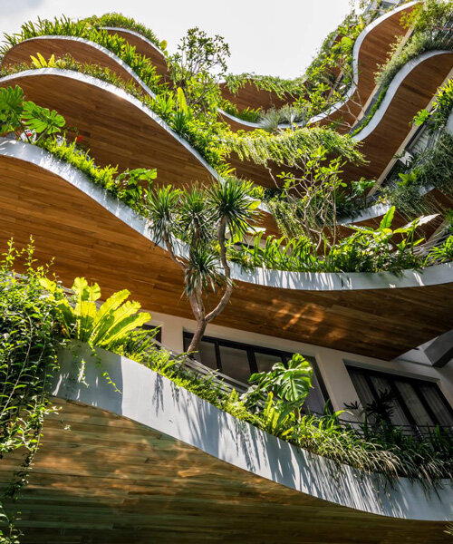 tropical plants cascade from the undulating balconies of this apartment building in vietnam