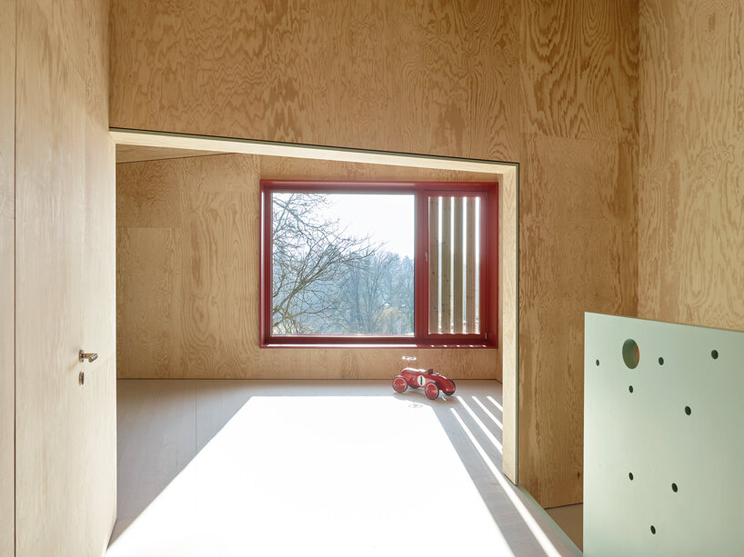 an angular timber house is planned around an old tree in bex, switzerland