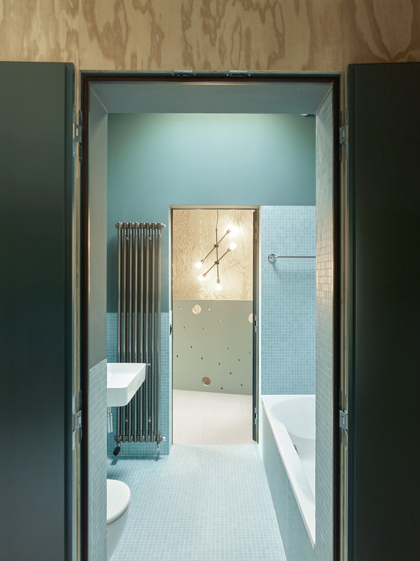 an angular timber house is planned around an old tree in bex, switzerland