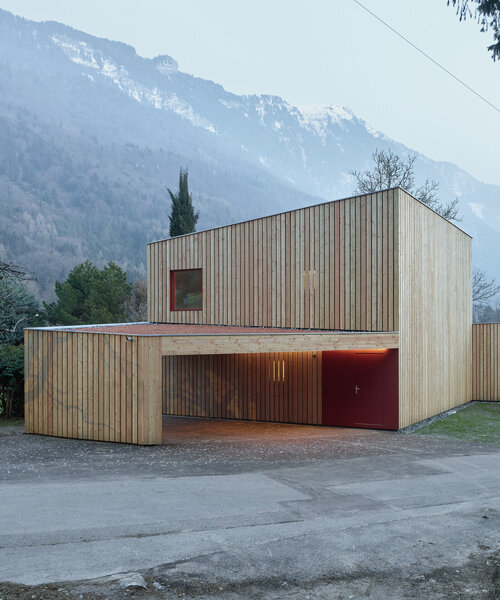 an angular timber house is planned around an old tree in bex, switzerland