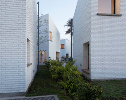 seven rotated brick-clad volumes frame a cluster of equal yet unique houses in argentina