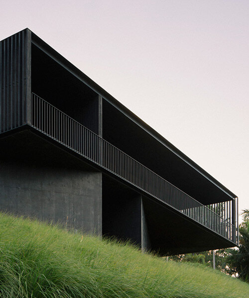 edition office anchors black concrete residence with timber batten shell to australian hilltop