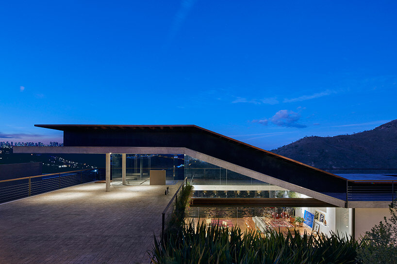 tetro tops residence with irregular deck roof opening towards mountainous views in brazil