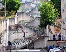 a giant snake moves down a massive staircase in this graffiti by SFHIR in portugal