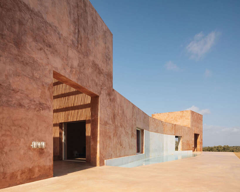 pigmented lime mortar + cork clad this vacation home beside long swimming pool in portugal