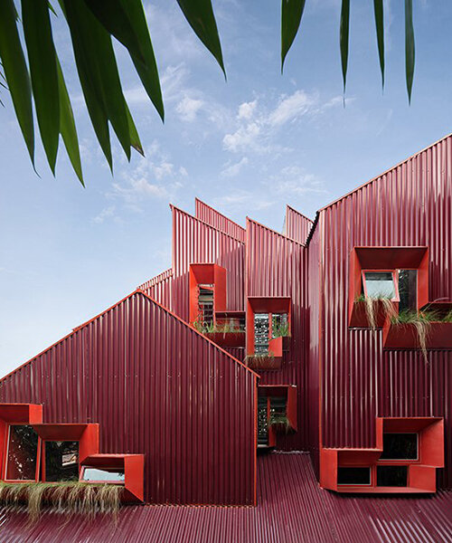 corrugated iron-clad stacked masses assemble this red house in indonesia