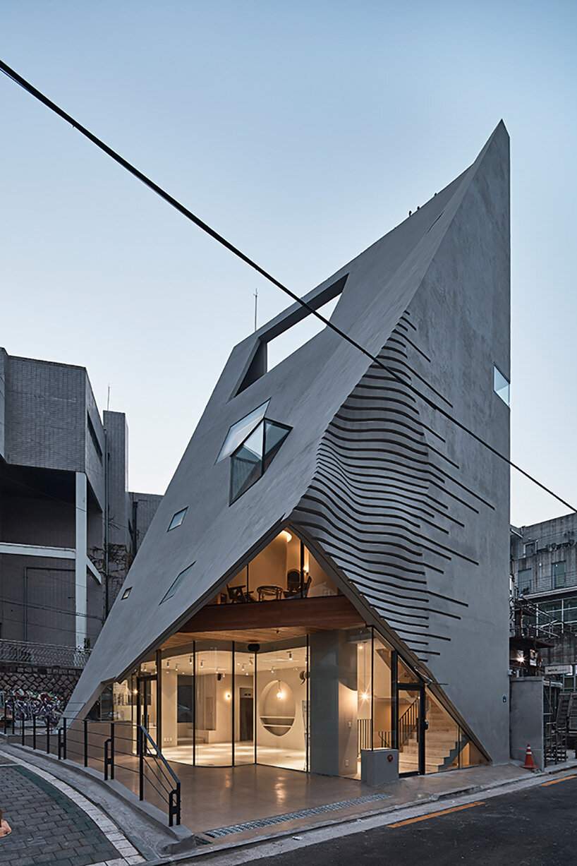 concrete pyramidoid spa with diverse cutouts stands out in the dense urban fabric of seoul