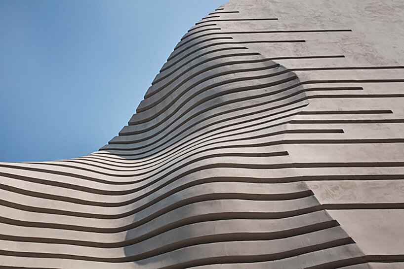 concrete pyramidoid spa with diverse cutouts stands out in the dense urban fabric of seoul