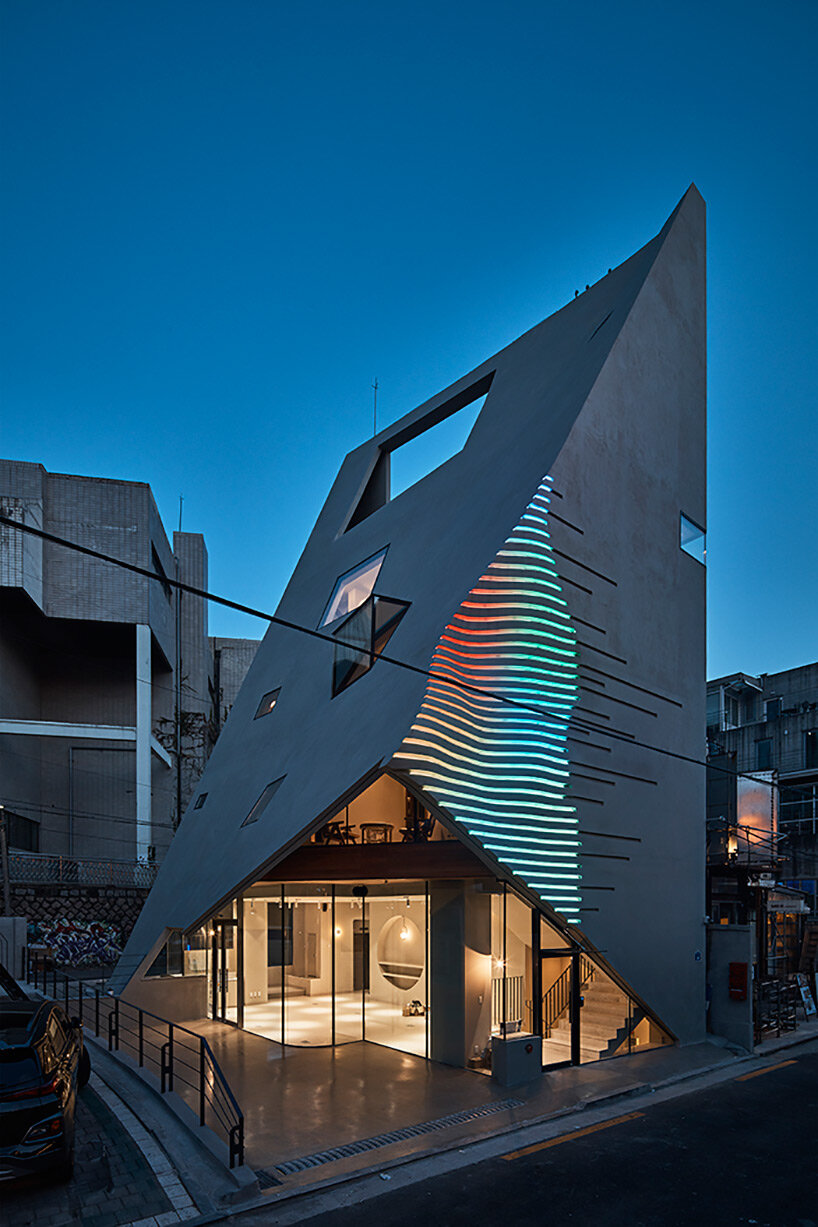 concrete pyramidoid spa with diverse cutouts stands out in the dense urban fabric of seoul