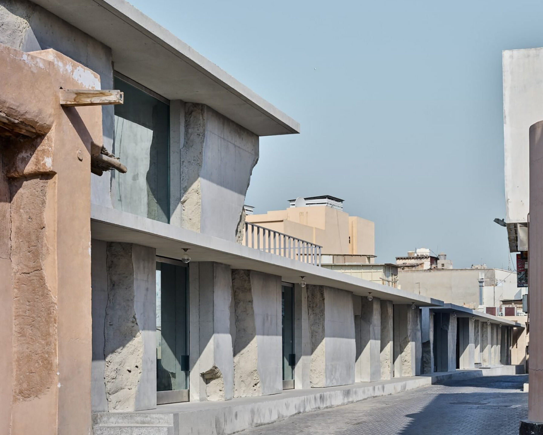 sand-casted concrete façade clads anne holtrop's green corner building in  bahrain