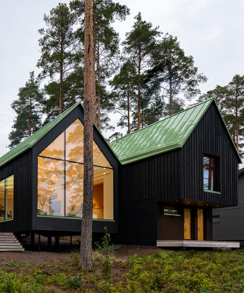 pirinen & salo sets three-volume charred wood house between pine trees in finland