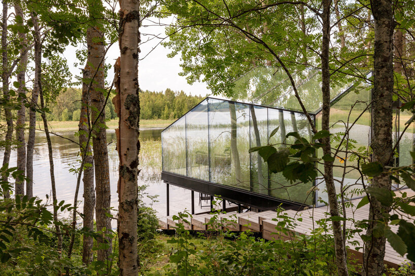 mirrored glass cabin with panoramic views disappears into finland's rich natural landscape