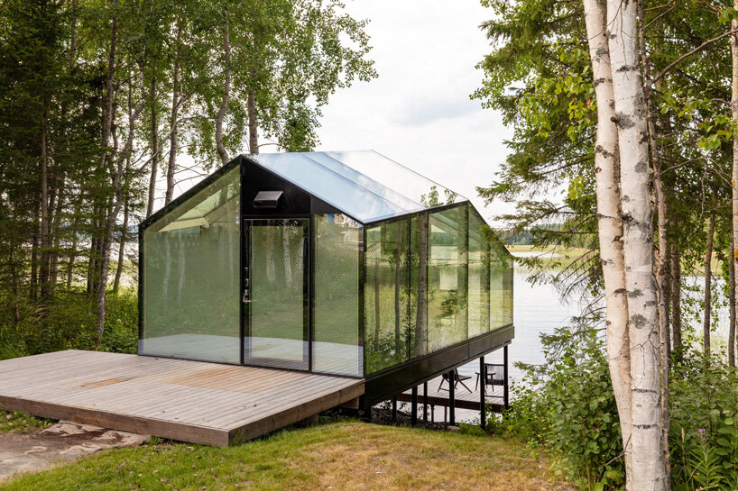 mirrored glass cabin with panoramic views disappears into finland's rich natural landscape