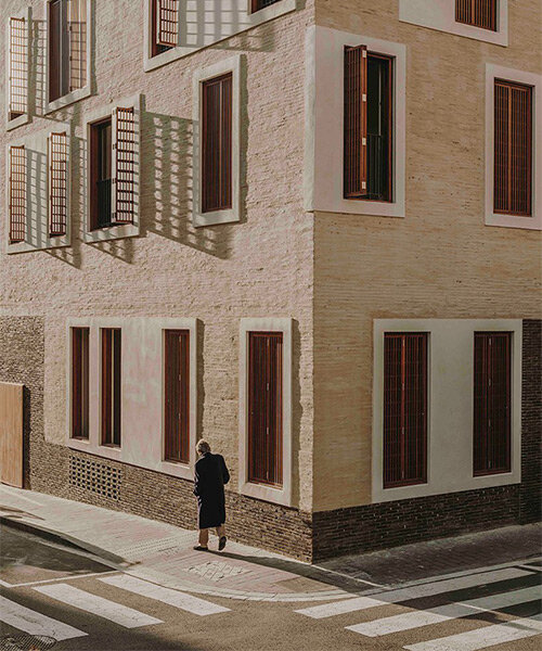 textured façades, wooden shutters and plinth detailing shape multi-dwelling building in barcelona