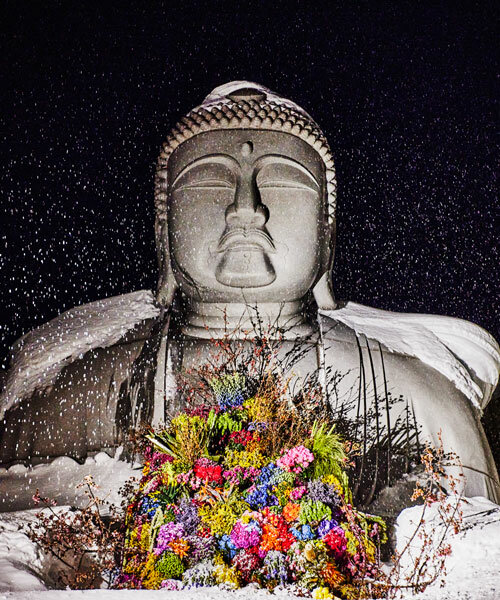 beneath tadao ando's hill, azuma makoto installs flower bouquet into arms of the buddha