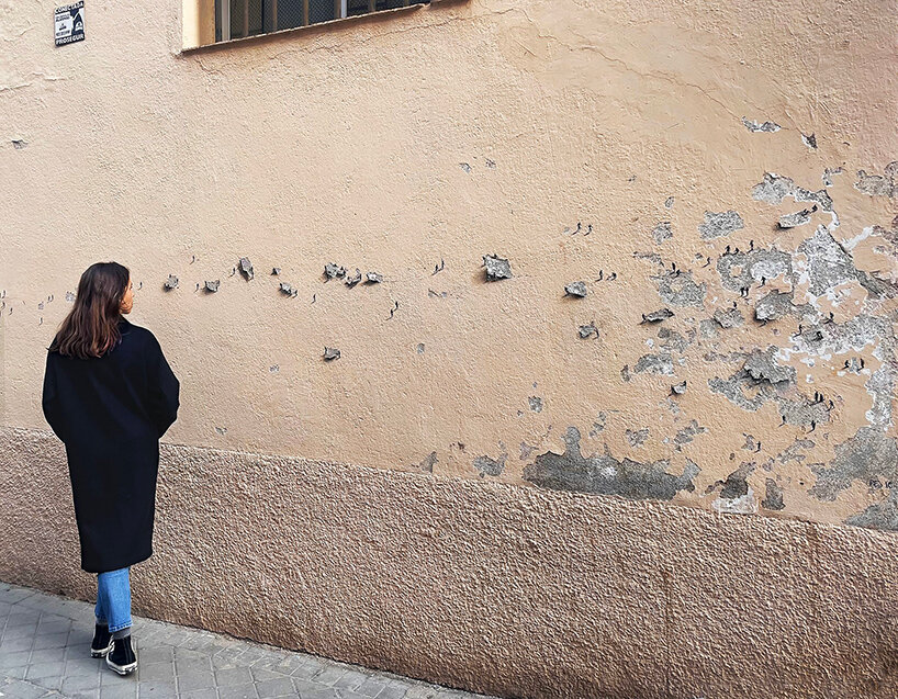 tiny figures by urban artist pejac emerge from the cracks of peeling walls in madrid 