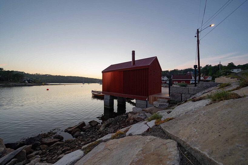 red-painted wooden cladding envelopes tiny boathouse by handegård arkitektur in finland