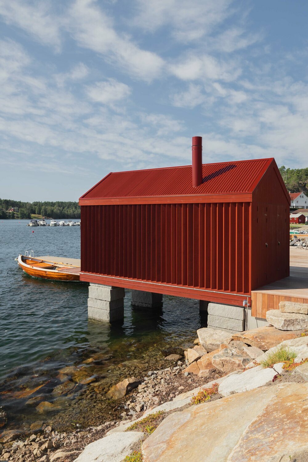 red-painted wooden cladding envelopes tiny boathouse by handegård arkitektur in finland