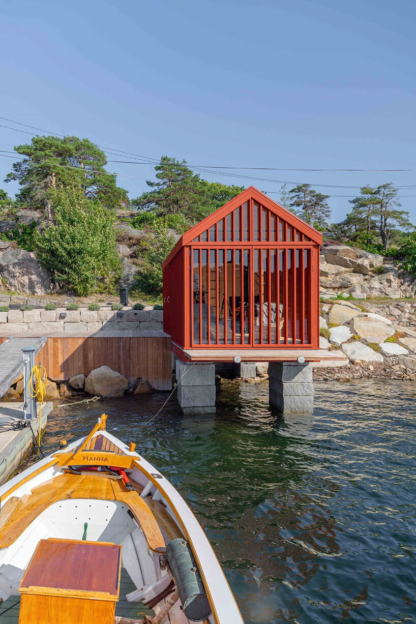 red-painted wooden cladding envelopes tiny boathouse by handegård arkitektur in finland