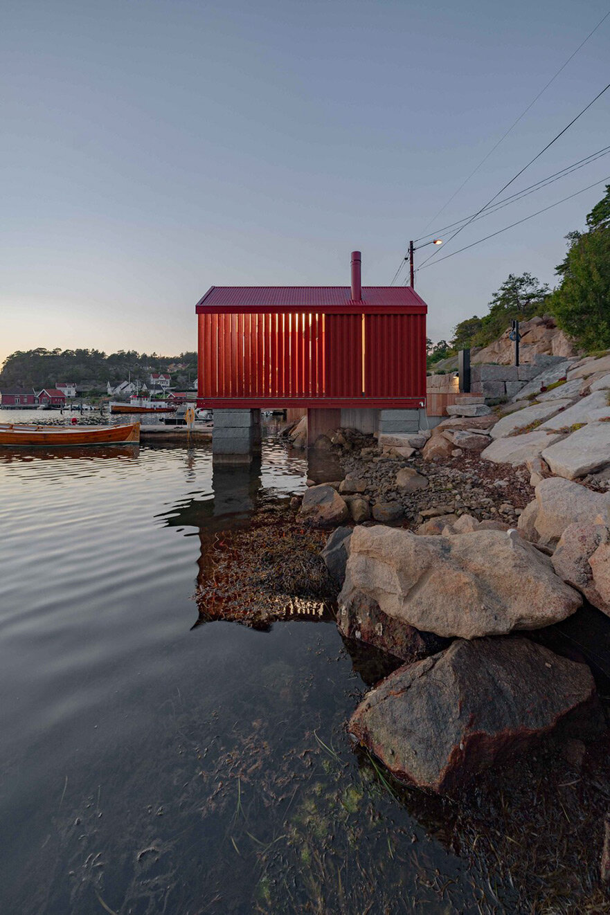 red-painted wooden cladding envelopes tiny boathouse by handegård arkitektur in finland