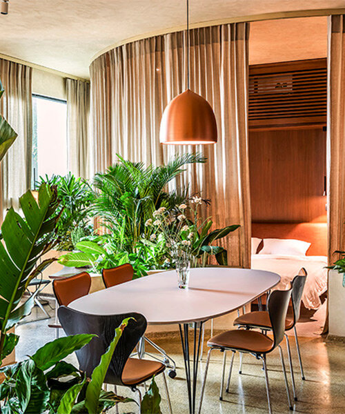 scandinavian furniture peeks through tropical plants in vietnamese residence by studio anettai