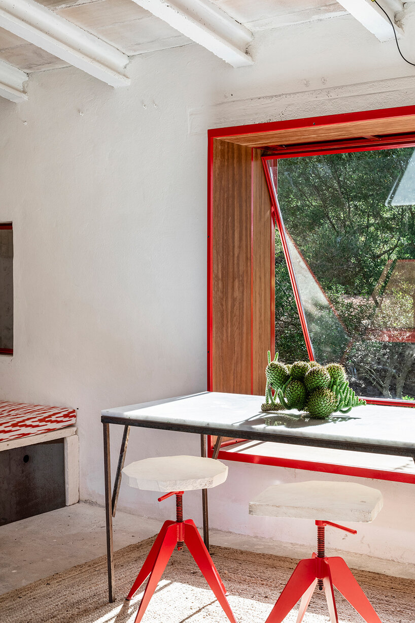 Red window pops out of Mariana de Delás' traditional stone shelter renovation in Mallorca