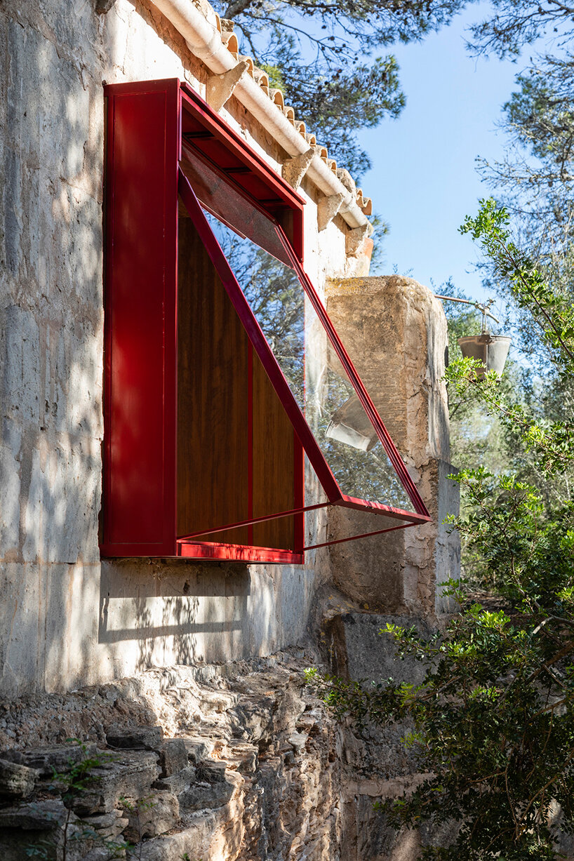 Red window pops out of Mariana de Delás' traditional stone shelter renovation in Mallorca