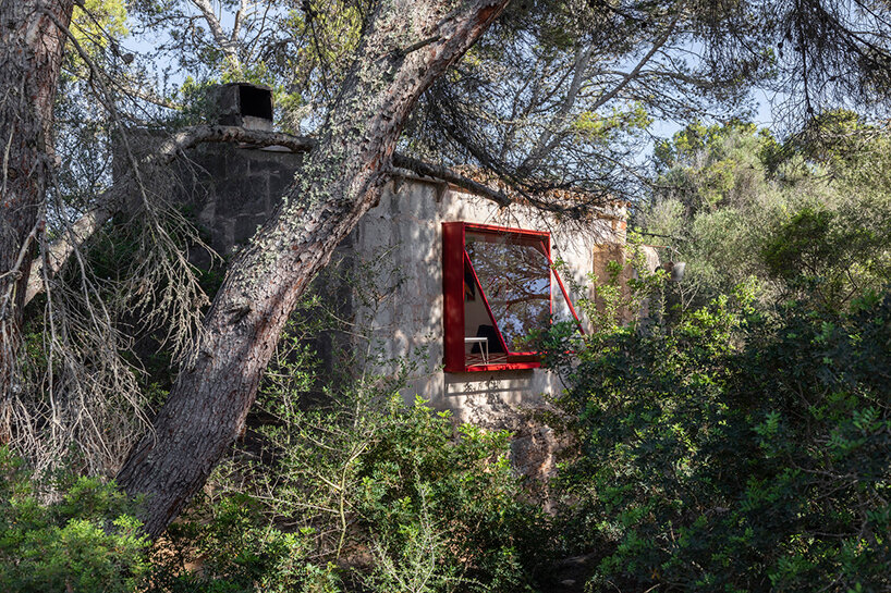 Red window pops out of Mariana de Delás' traditional stone shelter renovation in Mallorca