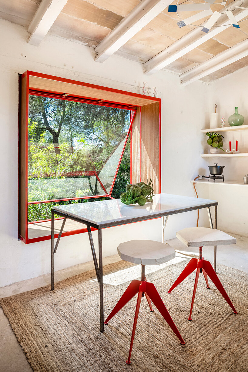 Red window pops out of Mariana de Delás' traditional stone shelter renovation in Mallorca