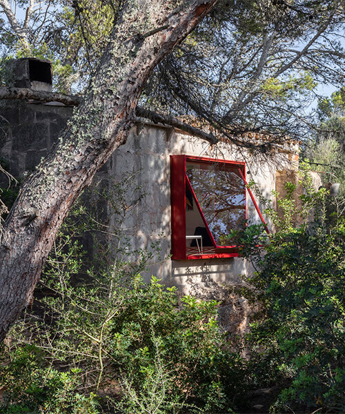 Red window pops out of Mariana de Delás' traditional stone shelter renovation in Mallorca