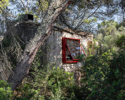 Red window pops out of Mariana de Delás' traditional stone shelter renovation in Mallorca