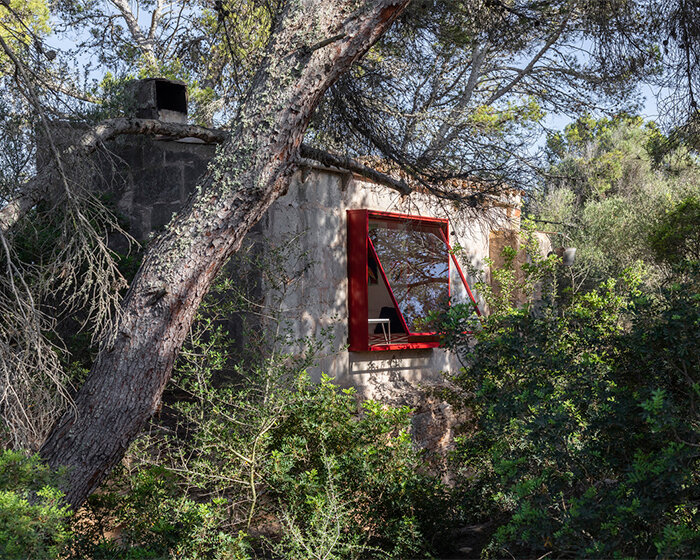 Red window pops out of Mariana de Delás' traditional stone shelter renovation in Mallorca