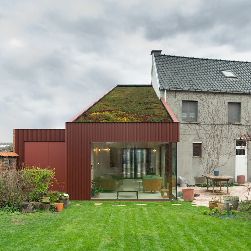 a green roof tops this red garden room extension in rural belgium
