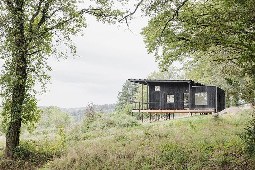 cantilevered wooden house by ciguë floats lightly above verdant field in france